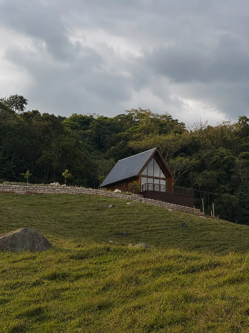 O chalé na encosta gramada, com a mata nativa atrás